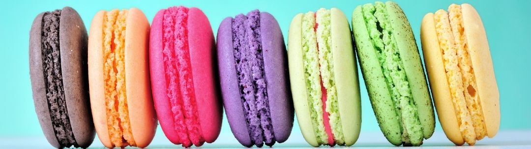 closeup of a row of colourful macarons on blue background