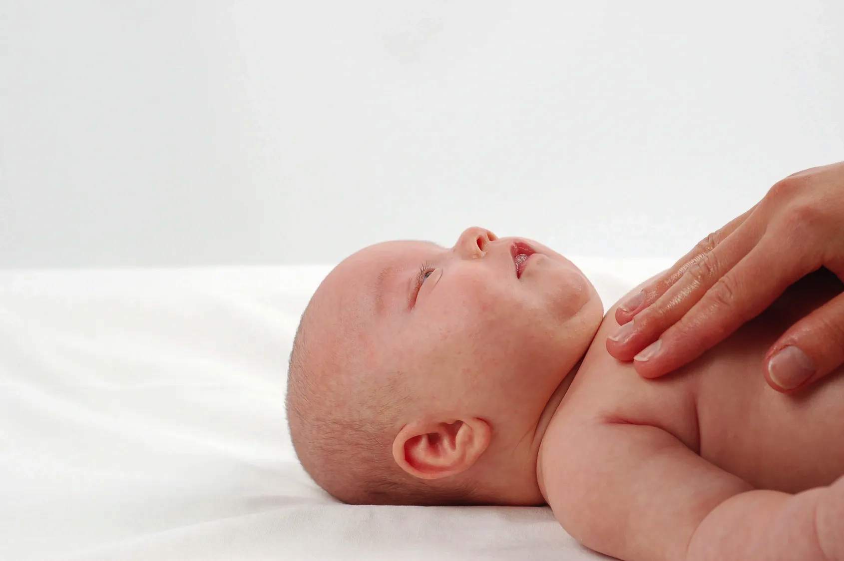 photo of baby with adult hand lightly touching it's chest