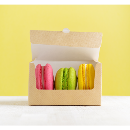 open box containing three macarons on white wooden table